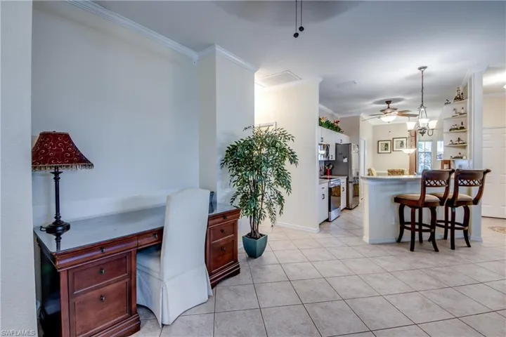 Home office featuring ceiling fan, light tile patterned flooring, ornamental molding, and built in desk