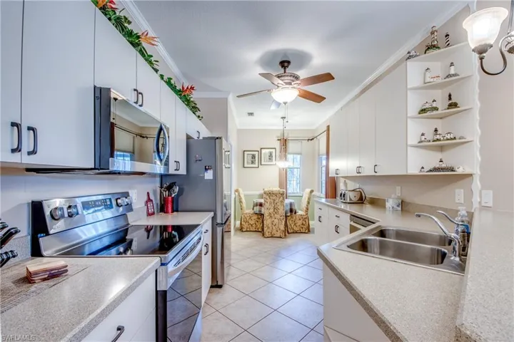 Kitchen featuring appliances with stainless steel finishes, crown molding, open shelves, light countertops, and hanging light fixtures
