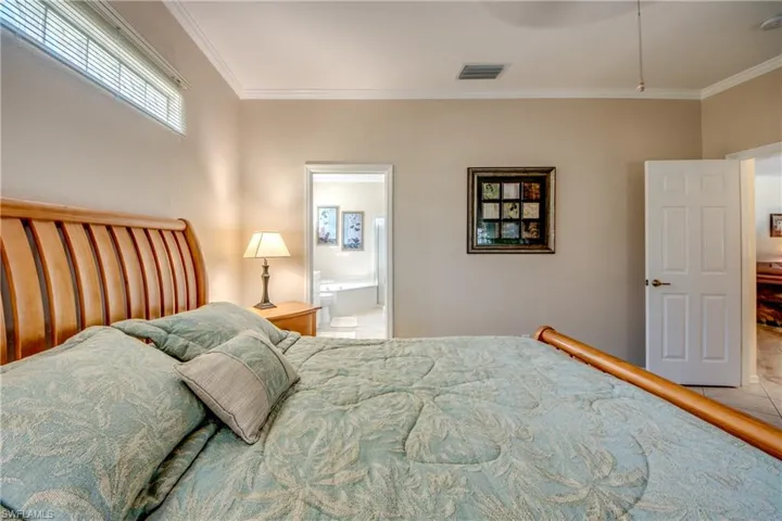 Bedroom featuring ornamental molding, ensuite bath, and a ceiling fan