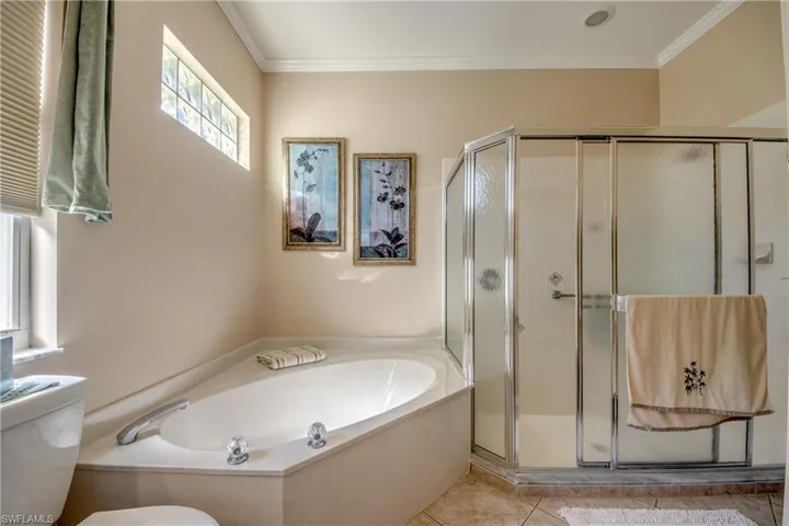 Full bathroom featuring a garden tub, crown molding, a shower stall, and tile patterned flooring