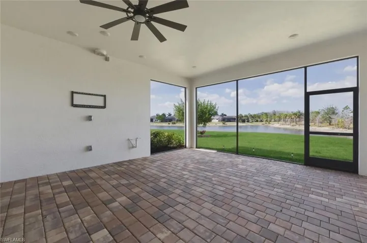 Unfurnished sunroom featuring ceiling fan, a water view, and a patio