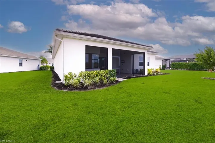 Back of property with a lawn, a sunroom, and stucco siding