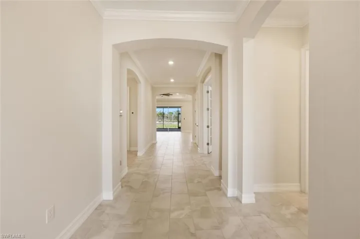 Corridor with arched walkways, crown molding, and recessed lighting