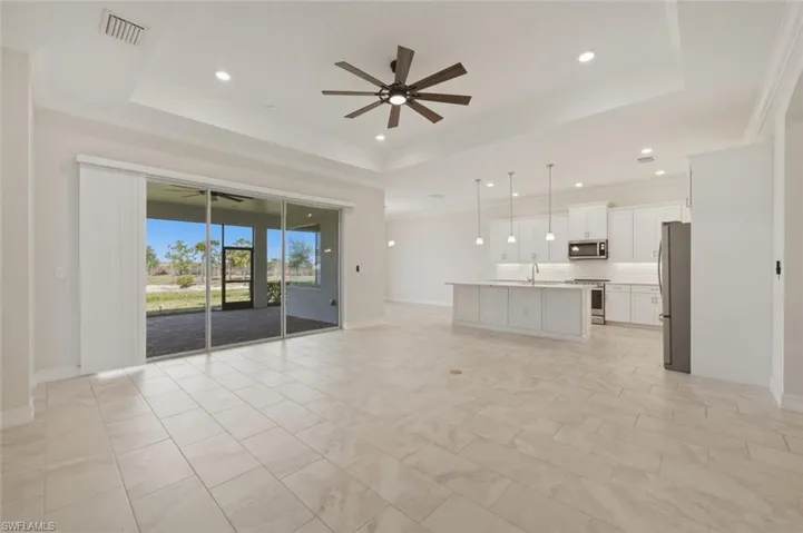 Unfurnished living room with a tray ceiling, ceiling fan, crown molding, and recessed lighting