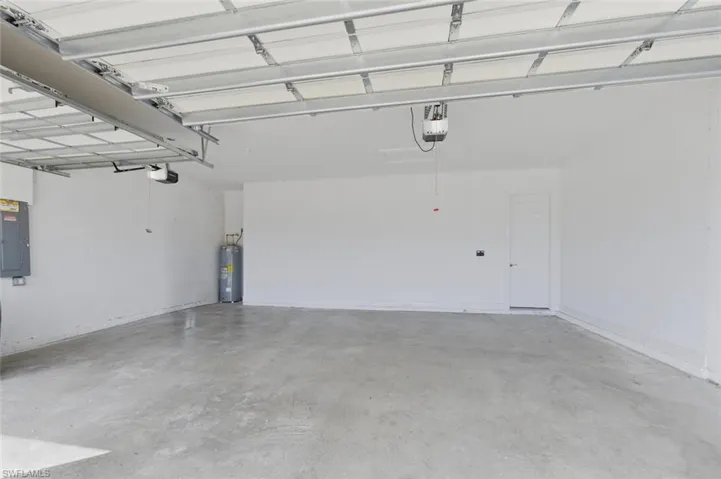 Garage featuring electric panel, water heater, and a garage door opener