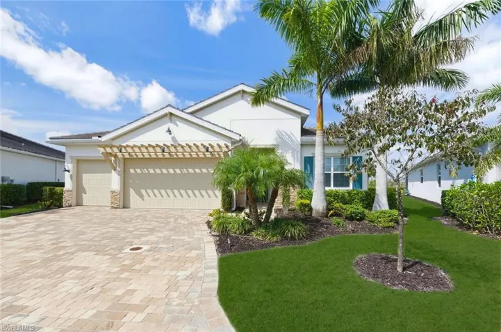 View of front of home with a garage, stucco siding, driveway, a front yard, and stone siding