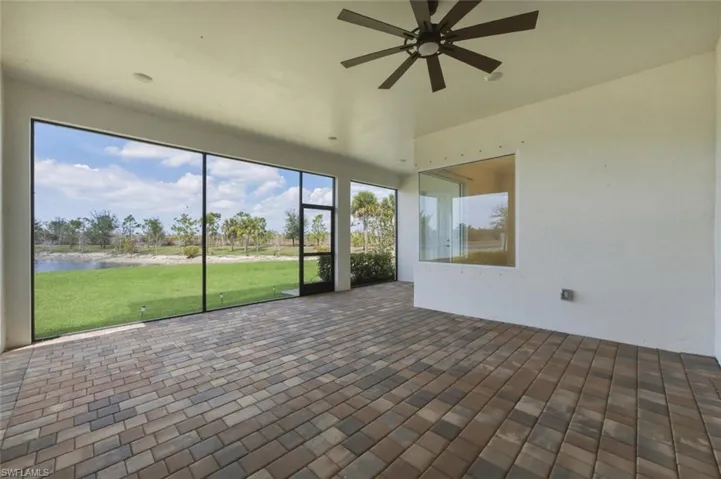 Unfurnished sunroom with ceiling fan, a water view, and a patio