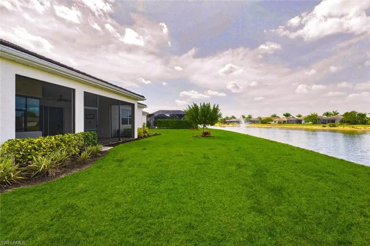View of grassy yard featuring a sunroom, a water view, and a residential view