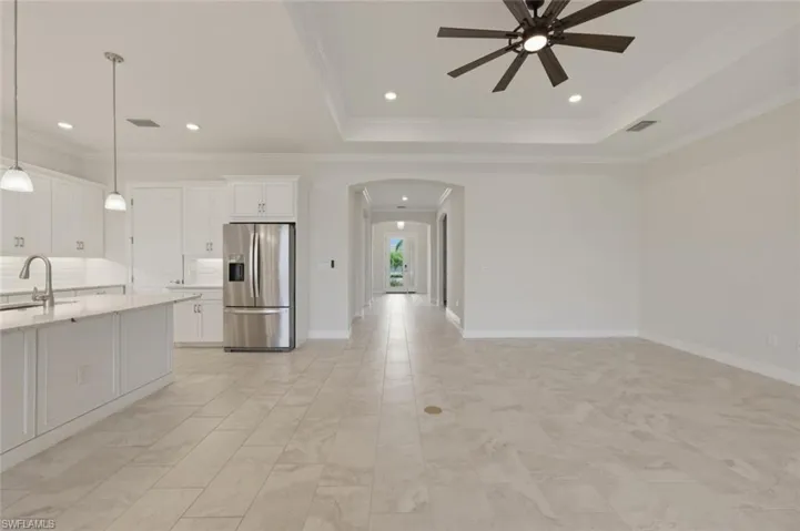 Kitchen with arched walkways, stainless steel refrigerator with ice dispenser, white cabinets, pendant lighting, and a ceiling fan