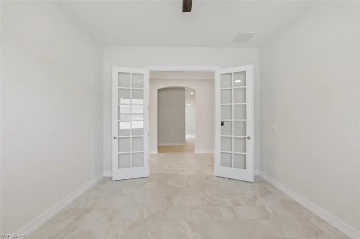 Spare room featuring arched walkways, french doors, and ceiling fan