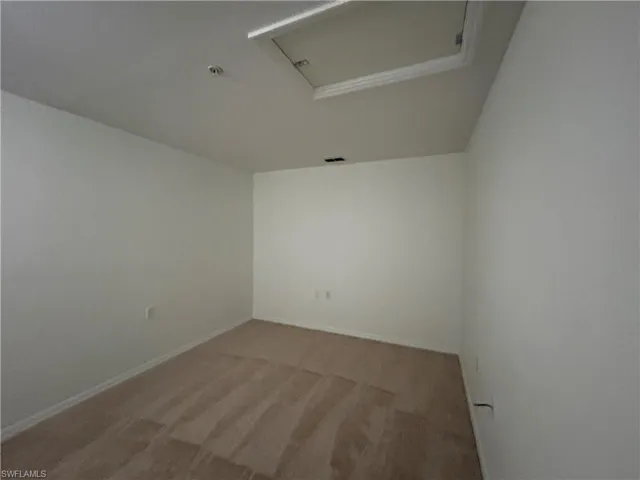 Empty room with attic access and light carpet