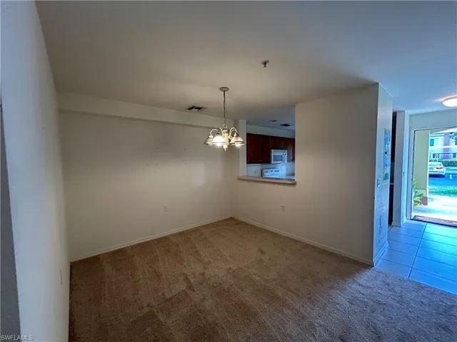 Unfurnished room featuring light carpet, a chandelier, and light tile patterned flooring