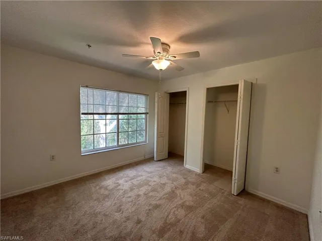 Unfurnished bedroom with two closets, carpet floors, a textured ceiling, and ceiling fan