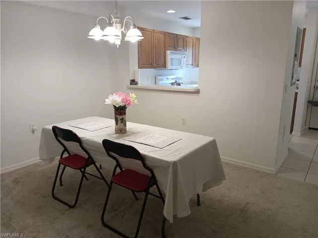 Dining area with light colored carpet and a chandelier