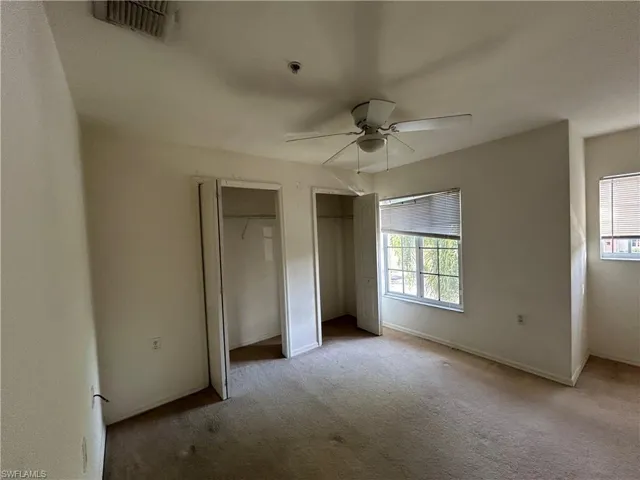 Unfurnished bedroom with two closets, carpet floors, and ceiling fan