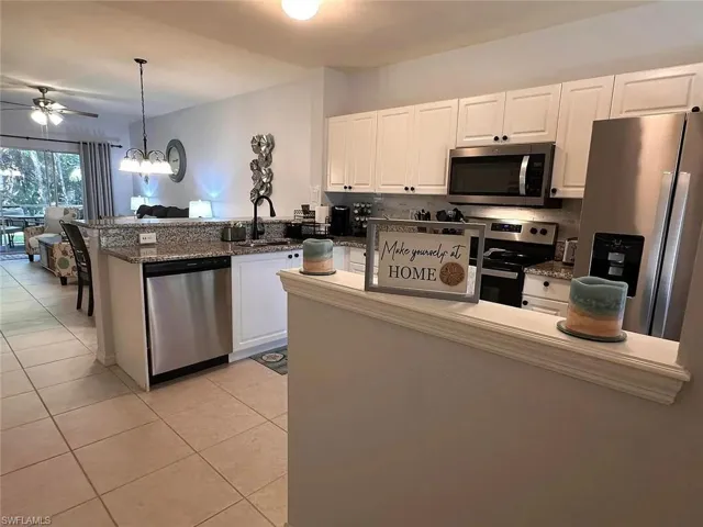 Kitchen with appliances with stainless steel finishes, a ceiling fan, a peninsula, and white cabinets
