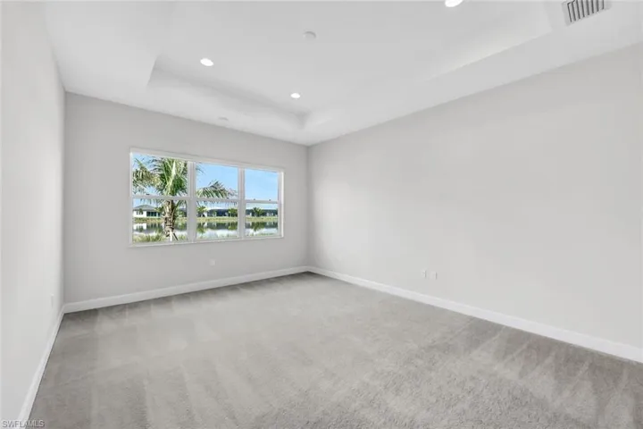 Primary Bedroom featuring a water view, a tray ceiling, and carpet floors