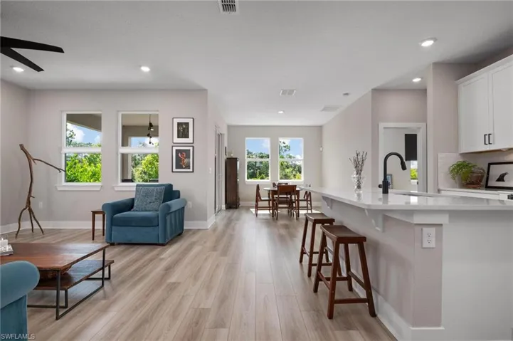 Kitchen with a kitchen breakfast bar, light hardwood / wood-style flooring, white cabinetry, and sink