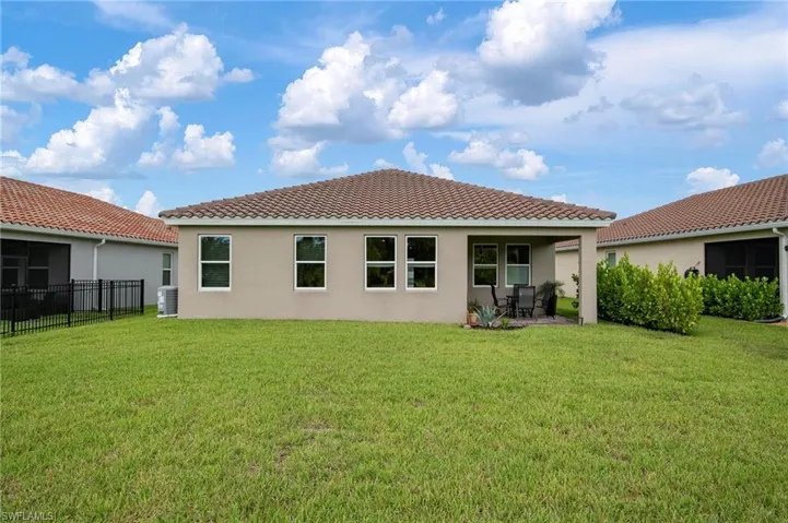 Rear view of house with a lawn and cooling unit