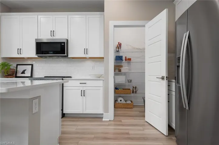 Kitchen with white cabinetry, appliances with stainless steel finishes, light hardwood / wood-style floors, and backsplash