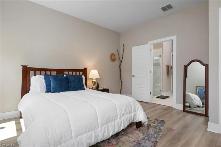 Bedroom with light hardwood / wood-style floors and connected bathroom