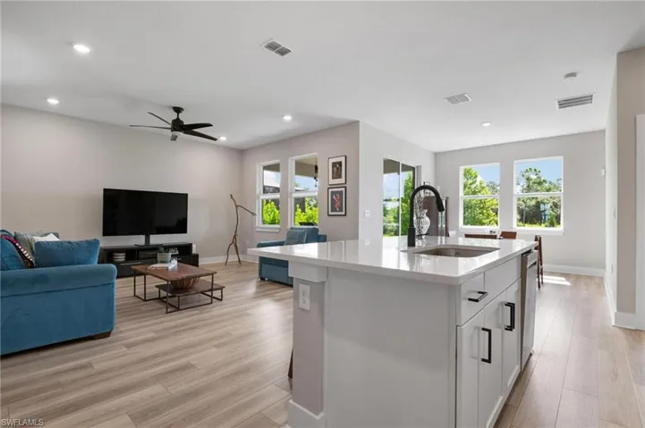Kitchen featuring white cabinetry, sink, an island with sink, light wood-type flooring, and ceiling fan