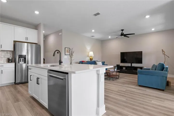 Kitchen featuring sink, light wood-type flooring, a center island with sink, and stainless steel appliances