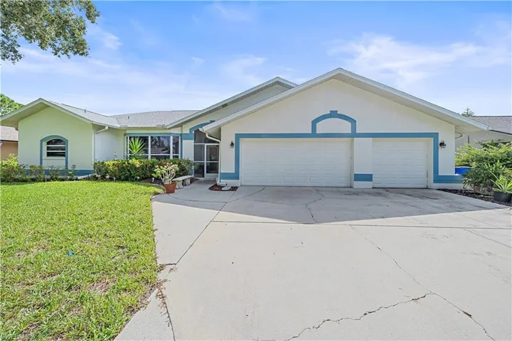 Ranch-style exterior with a two-car garage, concrete driveway, and front lawn