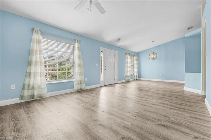 Unfurnished living room featuring vaulted ceiling, ceiling fan, and light wood-type flooring