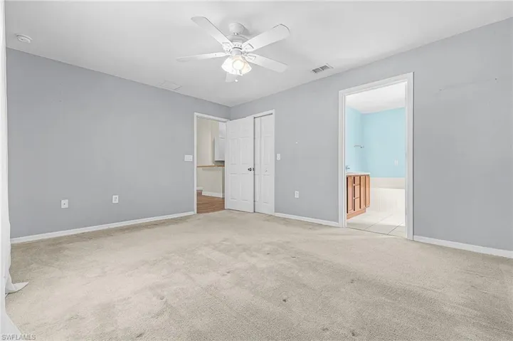 Unfurnished bedroom with a ceiling fan, light colored carpet, and ensuite bathroom