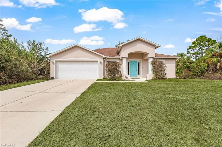 View of front of home with stucco siding, a front lawn, an attached garage, and concrete driveway