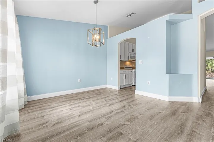 Unfurnished dining area featuring arched walkways, hanging lights, and light wood-type flooring