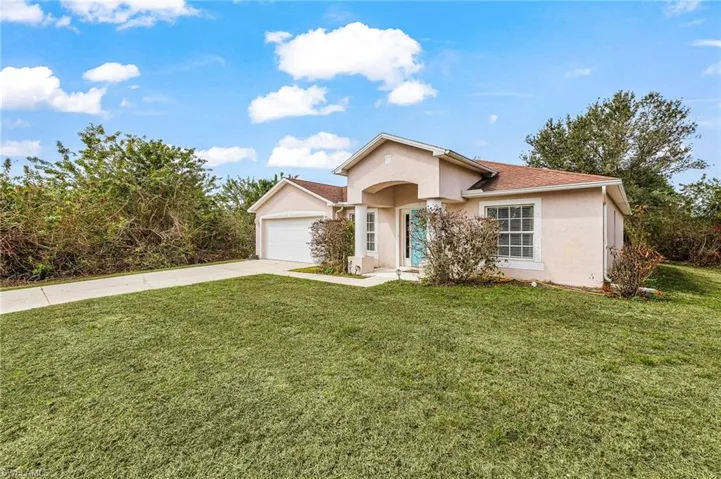 Ranch-style home with stucco siding, driveway, a front yard, and a garage