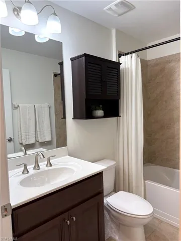 Full bathroom featuring toilet, tile patterned floors, vanity, and shower / tub combo with curtain