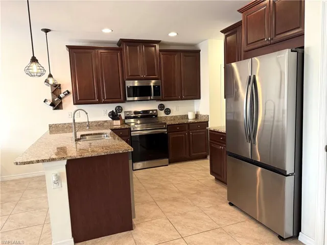 Kitchen with pendant lighting, a kitchen bar, kitchen peninsula, sink, and stainless steel appliances