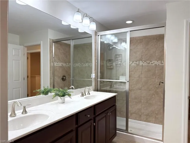 Bathroom featuring an enclosed shower, vanity, and tile patterned flooring