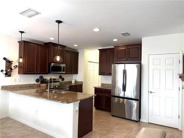 Kitchen featuring appliances with stainless steel finishes, kitchen peninsula, and decorative light fixtures