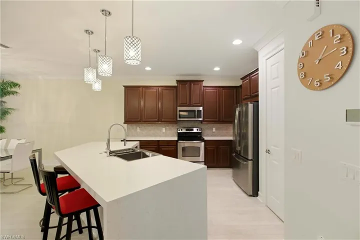 Kitchen featuring a breakfast bar area, decorative light fixtures, stainless steel appliances, backsplash, and ornamental molding