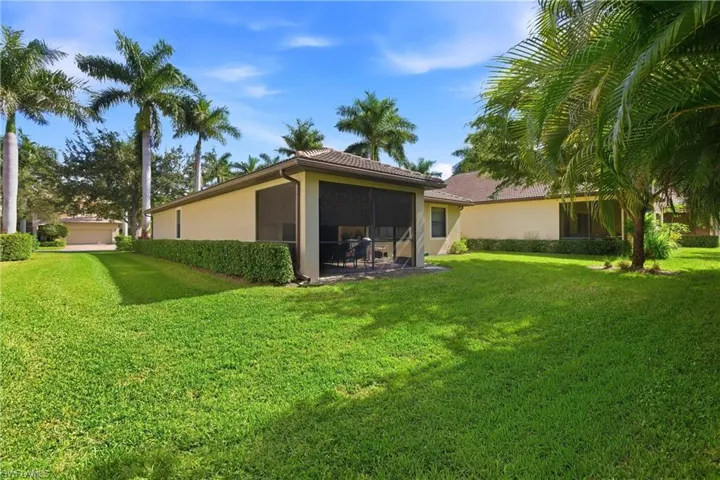 Rear view of property with a yard, stucco siding, and a sunroom