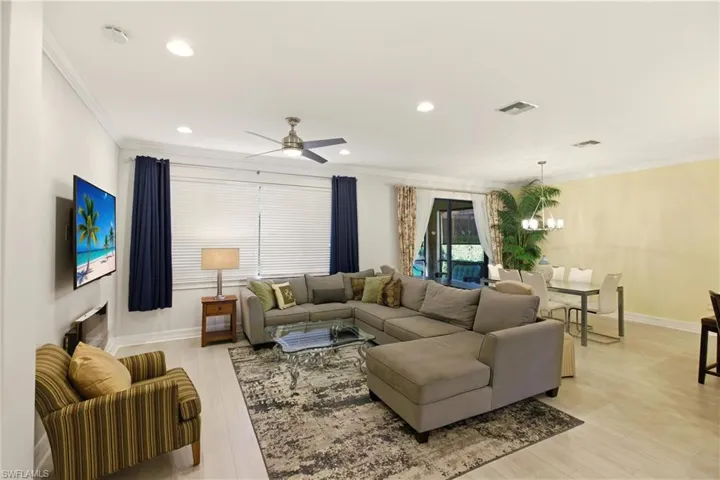 Living room featuring ceiling fan, light wood finished floors, a chandelier, ornamental molding, and recessed lighting
