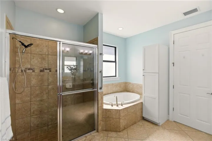 Bathroom featuring a stall shower, a garden tub, light tile patterned floors, and recessed lighting