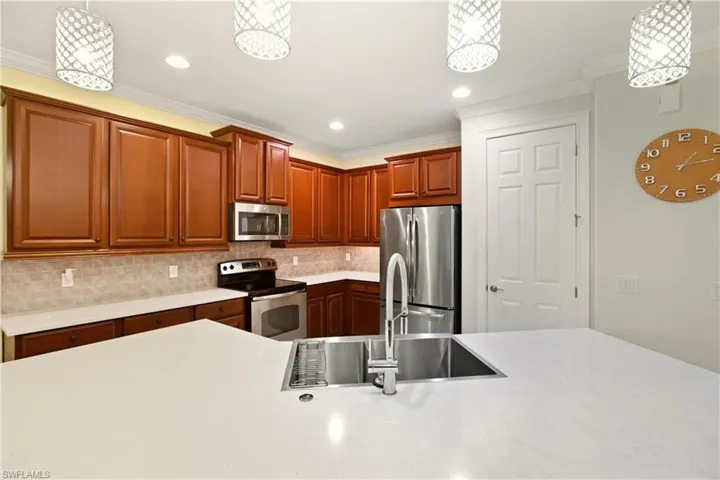 Kitchen featuring decorative light fixtures, stainless steel appliances, recessed lighting, crown molding, and decorative backsplash