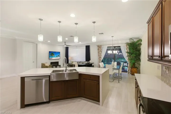 Kitchen featuring dishwasher, hanging light fixtures, black / electric stove, open floor plan, and a kitchen island with sink