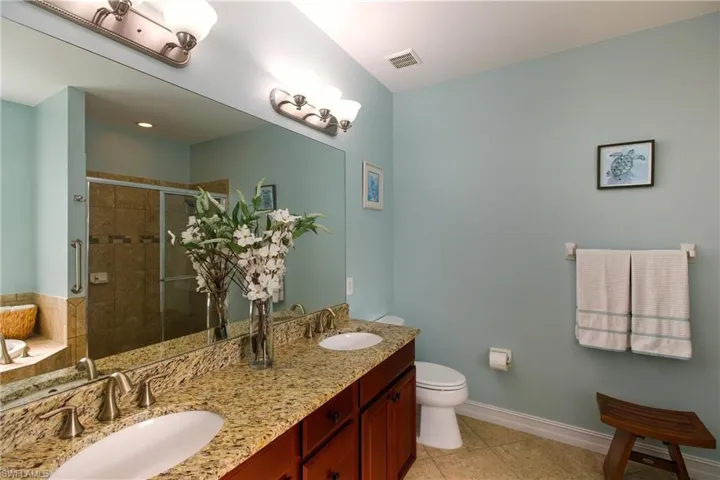 Full bath with double vanity and a shower stall