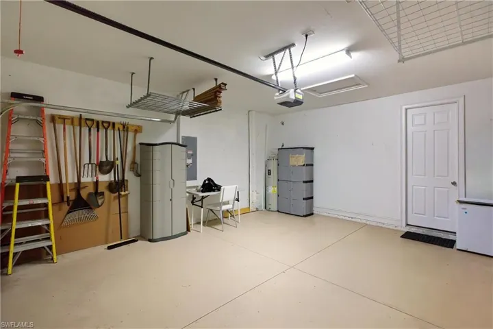 Garage featuring electric panel, water heater, and a garage door opener