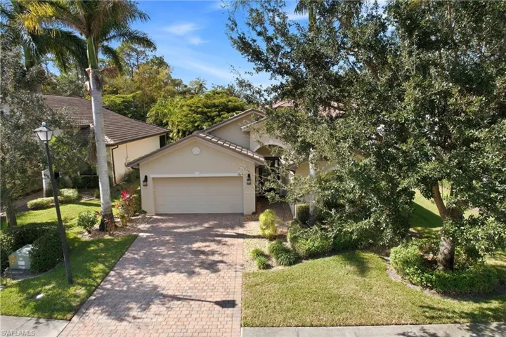 View of front of home with stucco siding, decorative driveway, a garage, a front lawn, and a tiled roof
