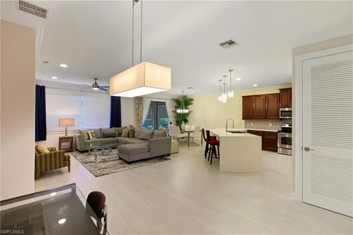 Living room featuring a ceiling fan, light wood-style floors, recessed lighting, a chandelier, and crown molding