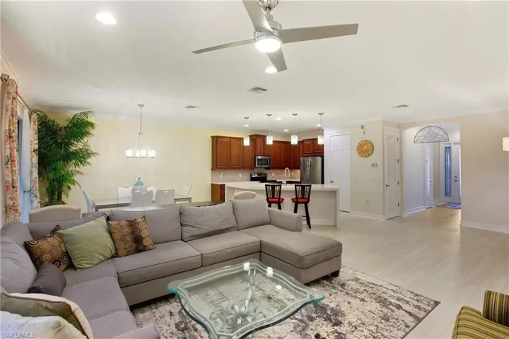 Living room with recessed lighting, a chandelier, a ceiling fan, light wood-style floors, and crown molding