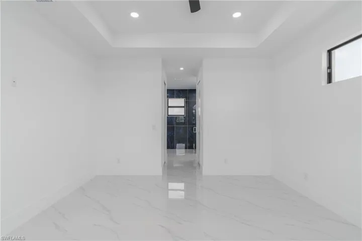 Empty room with a tray ceiling and light tile floors