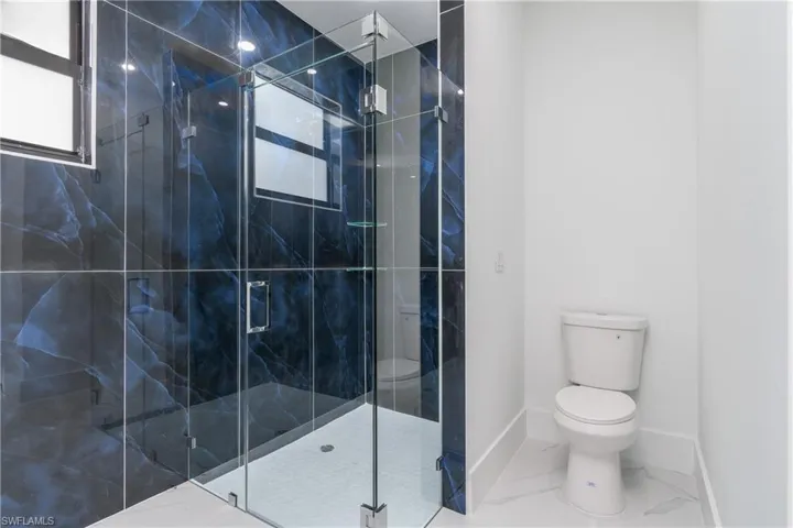 Bathroom with tile floors, a shower with door, and toilet
